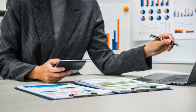 businesswoman works diligently at her desk, reviewing financial documents and analyzing investment