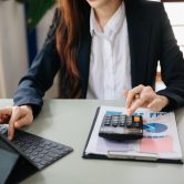 Woman hand business doing finances and calculate on desk about cost using on smartphone and tablet as concept